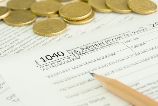 close-up income tax return form with golden coins on desk.
