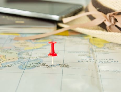 Embroidered red pins on a world map with a passport