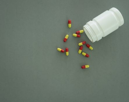 capsule spilling out of pills bottle on gray background. Top view