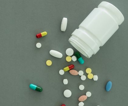 pills and pill bottle on gray background. top view.