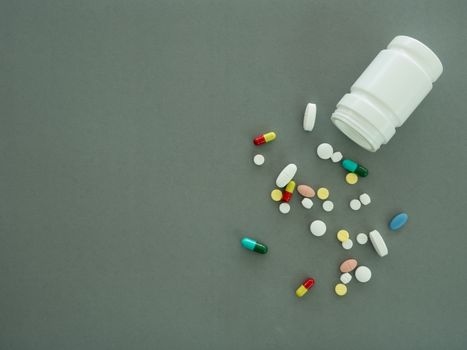 pills and pill bottle on gray background. top view.