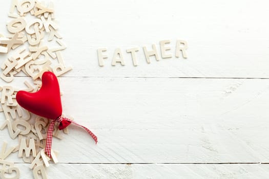 Image related to the celebration of Father's Day on white wooden background, wooden letters and a red heart view from above