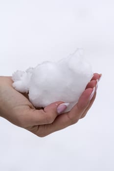 the girl with beautiful manicure holds a snow lump on a palm