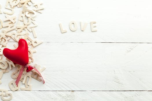 Love and red heart with a bow on white background and scattered letters view from above