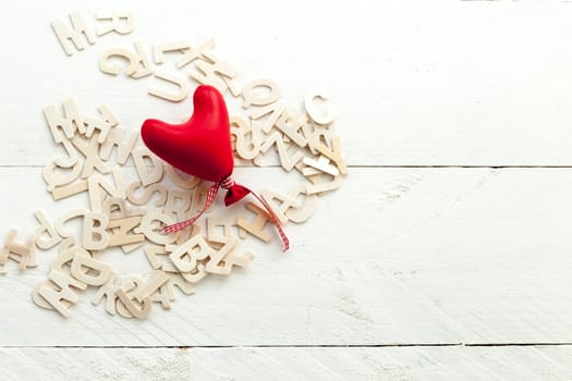 Love and red heart with a bow on white background and scattered letters view from above