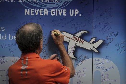 MALAYSIA, Kuala Lumpur: A man writes on a wall during a rally held in memory of MH370 missing flights victims after almost 2 years on search (on March 8, 2014) at The Square, Publika in Kuala Lumpur on March 6, 2016.