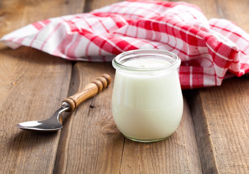 Delicious, nutritious and healthy yogurt in a glass jars with spoon on wooden background