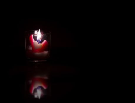 Heart shaped candles on black background