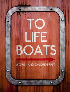 A Grungy Sign Pointing To Life Boats On An Old Ship