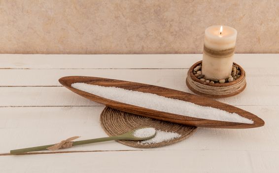 Mineral bath salts and aromatherapy candle on rustic white wood planks
