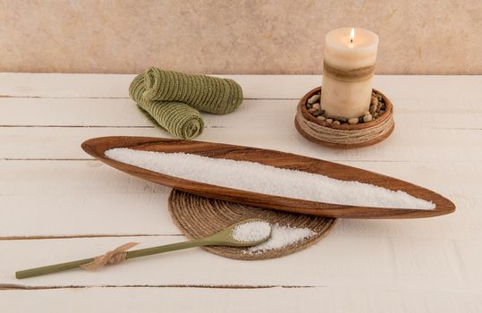 Revitalizing bath salts and aromatherapy candle on rustic white wood plank background