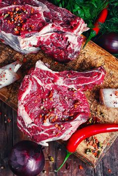 Chopped pieces of raw beef with spices on wooden cutting board