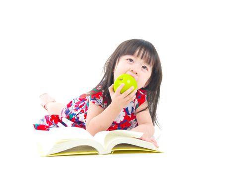 Asian girl reading a book and eating an apple.