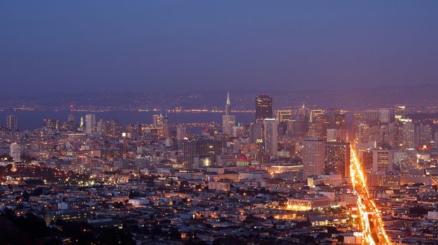 Downtown San Francisco at dusk viewed from Twin Peaks with Market Street in the foreground.