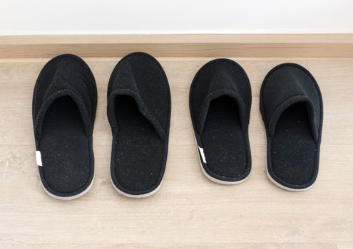 Black home slippers on wooden floor