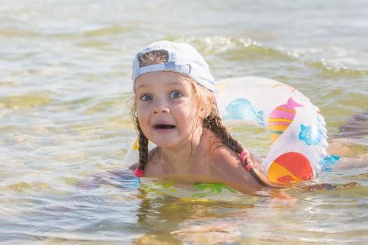 Four-year girl swims in the water with wearing the swimming circle