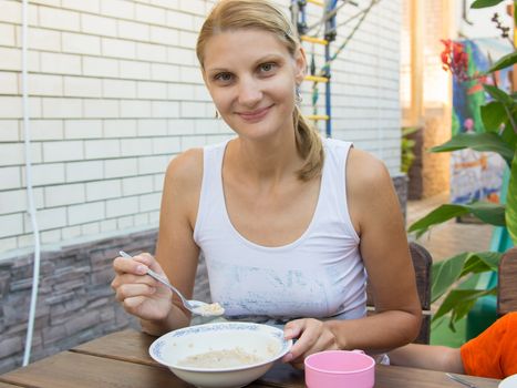 Twenty-five girl eating delicious porridge breakfast on the veranda