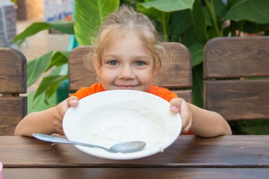 Five-year girl ate all the porridge in a plate and shows an empty cup