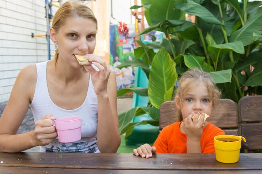 pretty young mother and five year old daughter having breakfast on the veranda