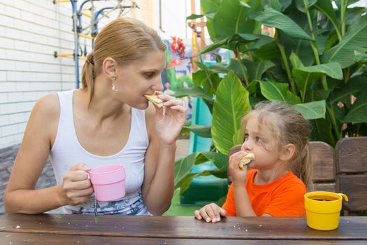 pretty young mother and five year old daughter having breakfast on the veranda