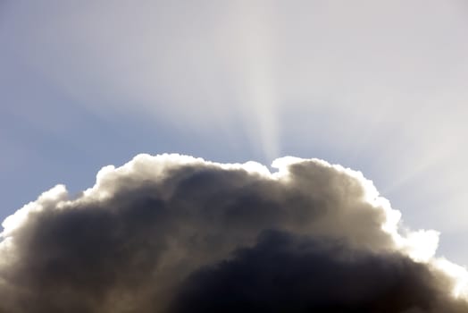 sun rays peering through the edge of a big fluffy cloud