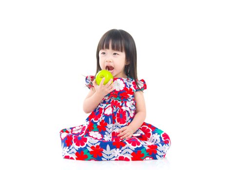 Cute asian girl sitting on the floor and holding an apple