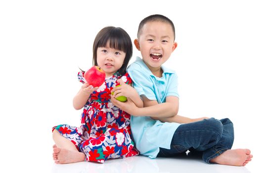 Asian brother and sister sitting on the floor and holding an apple