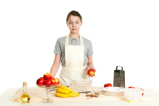the beautiful girl the teenager stands behind a kitchen table and holds apple