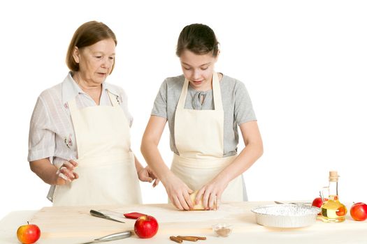 the grandmother and the granddaughter knead dough on a kitchen table