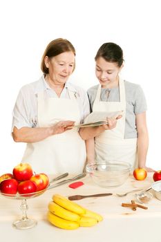 the grandmother and the granddaughter read the recipe-book before cooking of food