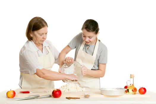 the grandmother and the granddaughter knead dough on a kitchen table