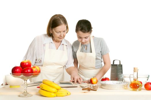 the grandmother and the granddaughter read the recipe-book before cooking of food