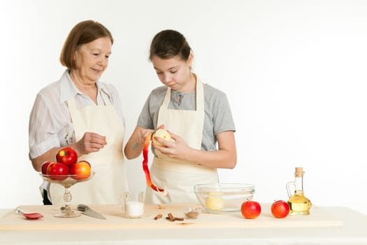 the grandmother and the granddaughter cut off a peel from apple for pie