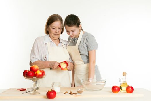 the grandmother and the granddaughter cut off a peel from apple for pie