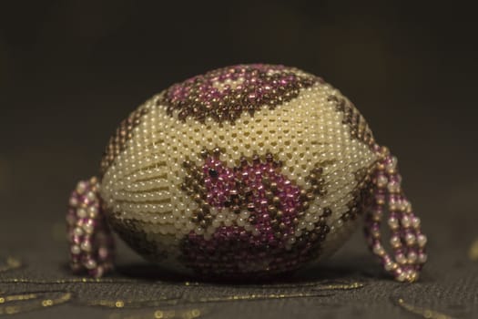 Easter Egg embroidered with colorful beads on a dark premise