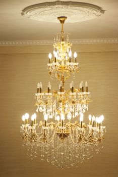 Beautiful crystal ancient chandelier in a hall. Lamp with soft yellow light