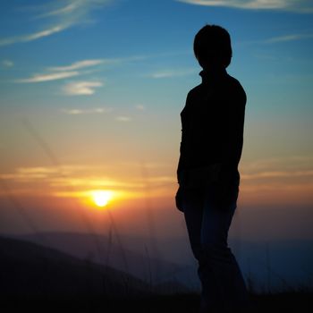 Silhouette of woman against sunset with orange clouds and sky