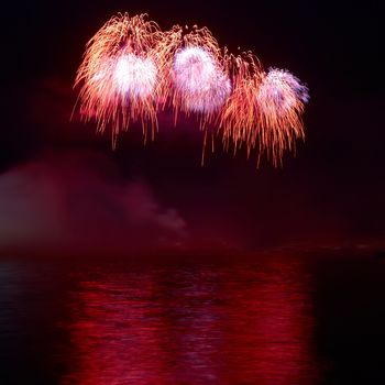 Red colorful holiday fireworks on the black sky background.