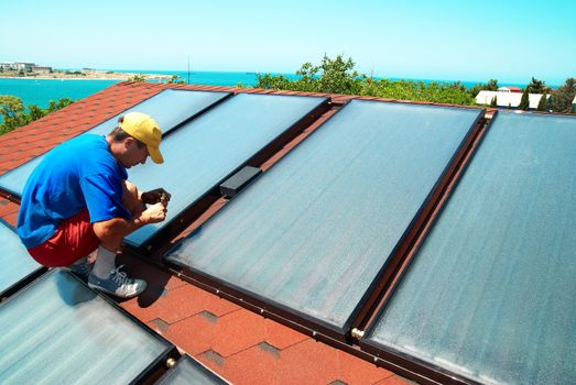 Worker mounting solar water heating panels on the roof.