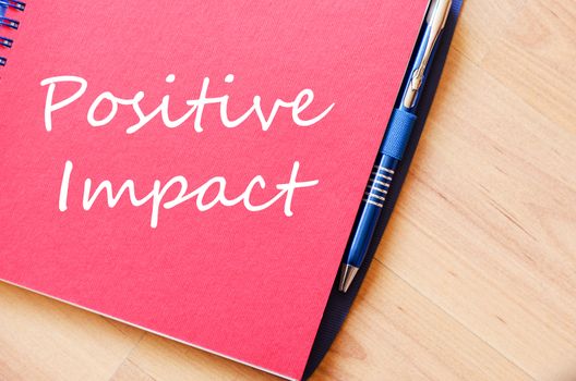 Positive impact text concept write on notebook with pen