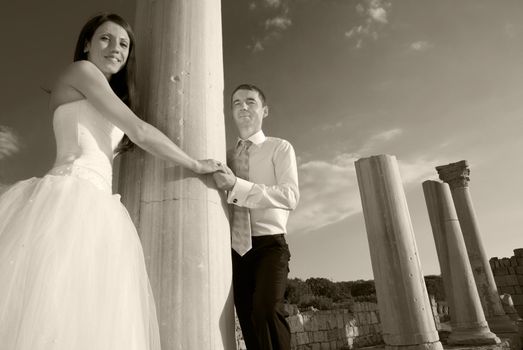 Beautiful wedding couple- bride and groom near greece column in the ancient city. Black and white, sepia