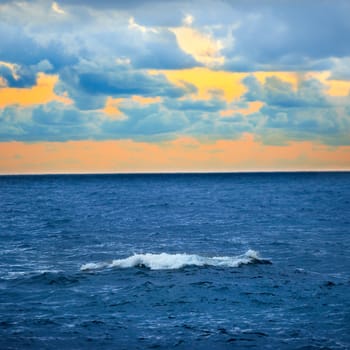 Big wave, colorful sunset over the sea with blue sky and clouds