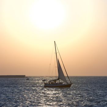 Sail boat against sea sunset. Colorful marine landscape.