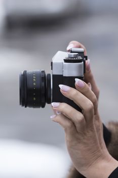 girl with a nice manicure holding vintage camera in the hands of