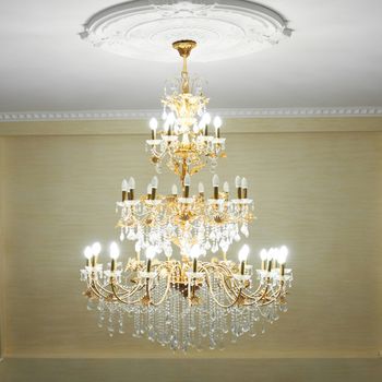 Beautiful crystal ancient chandelier in a hall. Lamp with soft yellow light