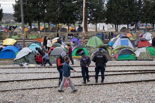 GREECE, Idomeni: Police remain vigilant on the outskirts of the Idomeni refugee camp in Greece on March 7, 2016. Thousands of refugees from the middle east remain stranded at the border of Greece and Macedonia. The situation has gotten worse at the refugee camp at Idomeni. People are living in tents, with no warm water or showers available. 