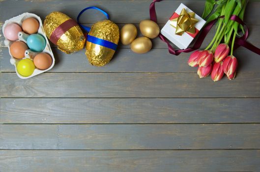 Easter eggs and spring tulips over a wooden table 