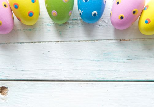 Decorated easter eggs on white wooden planks with space 