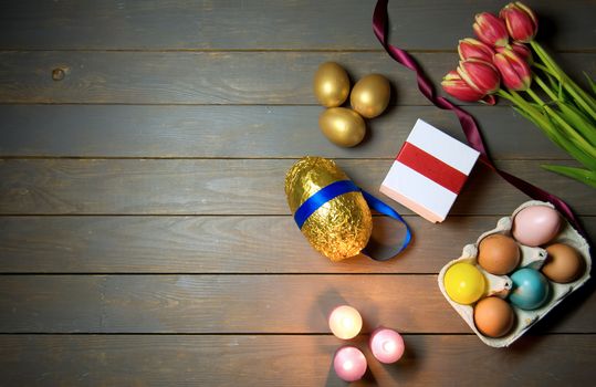 Easter eggs and lit candles wooden background