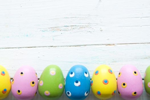 Decorated easter eggs on white wooden planks with space